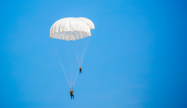 Skydiving. Flying parachutists against the background of the blue sky and mountains. Extreme sport and entertainment.