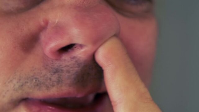 man picking nose close-up, inserting finger into nostril with casual gesture, everyday human behavior and hygiene issue, candid detail of bad habit and personal discomfort