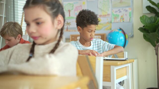 Students turn to retrieve their stationery from backpacks hanging behind their chairs, while students and teachers of diverse nationalities are engaged in activities in the background of this internat