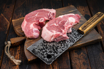Raw lamb chump chops with bone on rustic wooden board, fresh sirloin saddle cuts near butcher cleaver, premium red meat prepared for roasting or grilling recipes. © Mironov