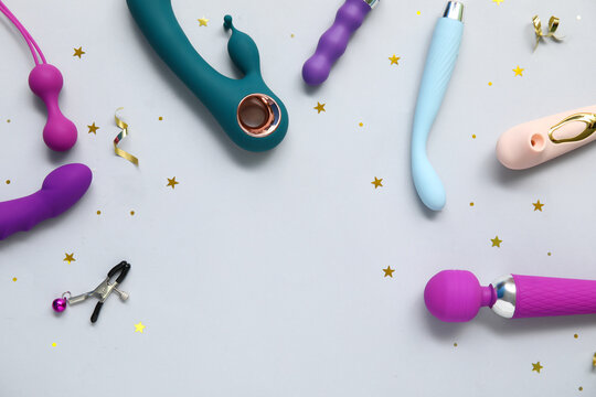 Different sex toys and confetti on grey background