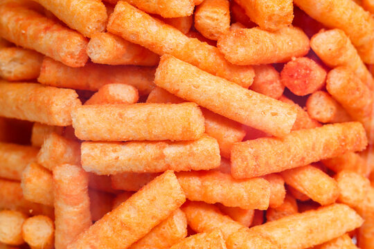 Close up crispy cheese stick snack texture, savory crunchy corn cheese sticks background, detailed macro food pattern with seasoning coating, appetizing snack.