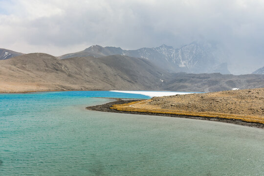 Turquoise Gurudongmar Lake in North Sikkim, India, surrounded by stark high-altitude terrain and rugged Himalayan peaks.