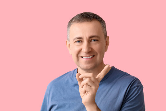 Mature man with contact lens on pink background
