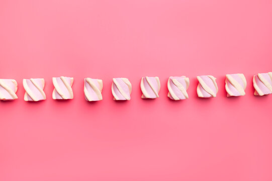 Scattered marshmallows on pink background flat lay top view. Sugar candies, sweet abstract background. Delicious dessert, pastel soft shades. Space for text