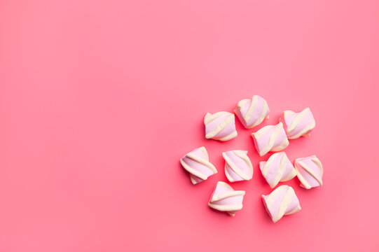 Scattered marshmallows on pink background flat lay top view. Sugar candies, sweet abstract background. Delicious dessert, pastel soft shades. Space for text