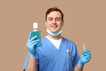 Male dentist with bottle of mouth rinse and floss toothpick on beige background. World Dentist Day