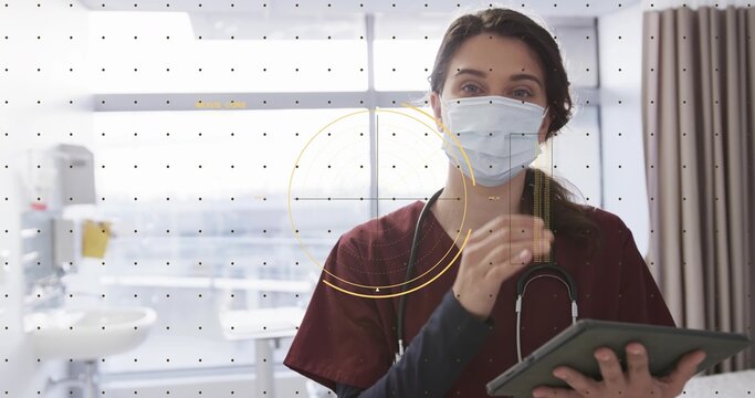 Standing female nurse reviewing tablet in hospital room, in maroon scrubs, stethoscope, HUD overlay