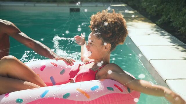 Woman reclining donut float laughing while friend splashing and tossing beach ball for lifestyle