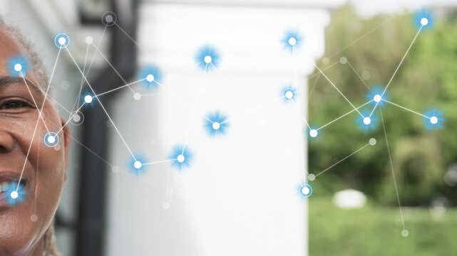 Senior woman watching blue nodes appearing near cheek, forming network over trim and hedge for tech