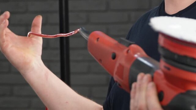 Professional Worker Buffing the Body from Light Scratches, Removing Swirls, Paint Defects from a Body of the Vehicle. A car service worker polishes the black car body with eccentric polishing machine.