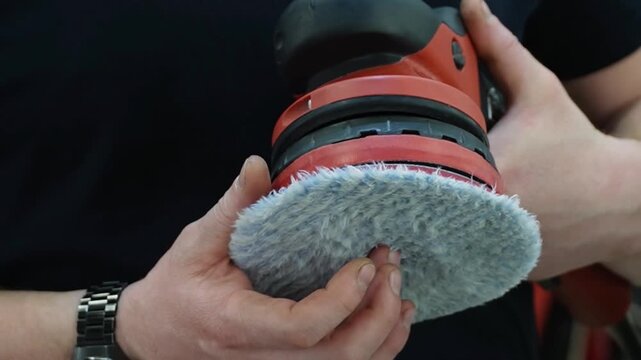 Professional Worker Buffing the Body from Light Scratches, Removing Swirls, Paint Defects from a Body of the Vehicle. A car service worker polishes the black car body with eccentric polishing machine.