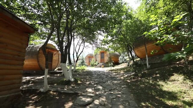 A tranquil view of rustic wooden cabins nestled on a grassy hillside among trees with white trunks, providing a peaceful mountain retreat in a beautiful and natural environment.