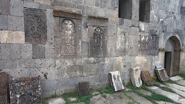  A slow pan reveals a historic stone wall adorned with intricately carved ancient Armenian khachkars. These beautiful stone crosses are a testament to rich cultural and religious heritage.