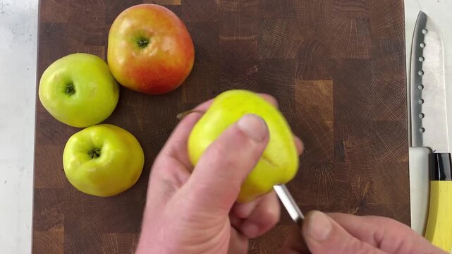 Hands coring a fresh apple on a wooden chopping board for healthy cooking and snack preparation.