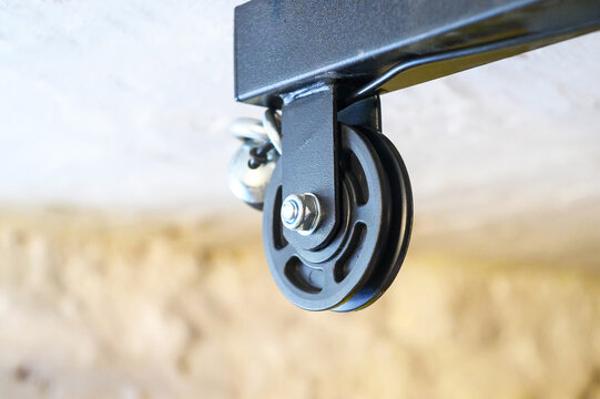 Close-up of a black pulley wheel attached to a metal frame with a bolt