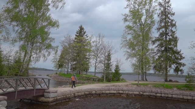 Quiet Lakeside Setting With Pedestrian Crossing Stone Bridge Amid Trees Under Overcast Skies. Creative