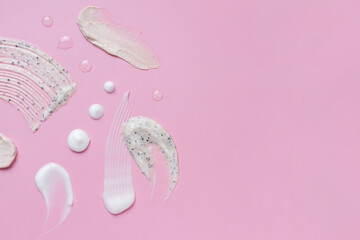 Fototapeta premium Cosmetic cream and scrub smears on pink background, skincare texture with exfoliating particles and droplets, beauty concept with copy space