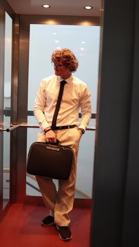 Vertical screen businessman waits in elevator checking time holding briefcase showing calm anticipation of colleague meeting business routine pause between tasks in office day