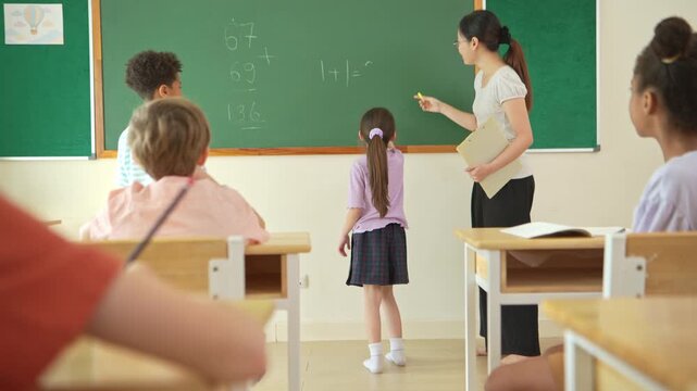 Schoolgirl solving math problem on chalkboard with teacher guidance in classroom, representing education and problem solving