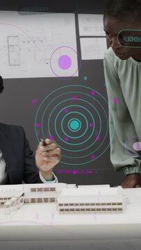 Vertical video: Architect pointing pen peer leaning reviewing model layout while teal HUD rising