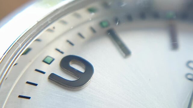 Macro view of an analog watch dial focusing on the number nine, featuring silver metallic texture and minute markers, concept for time management and precision