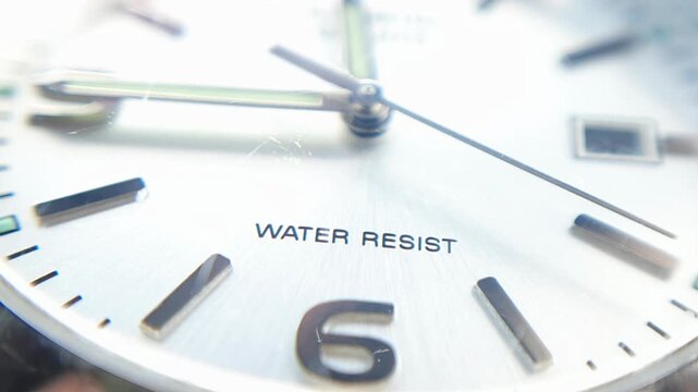 Macro view of silver watch face with number six, hour hand, and water resistant text, elegant analog clock dial for time management and business concepts