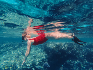Undersea View of Woman Snorkeling in Red Sea, Egypt, Floating Over Coral Reef © Dmitri