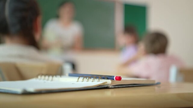 Notebook and pencil on desk with blurred classroom background, ideal for copy space and education concept