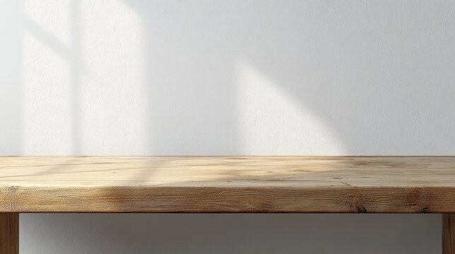 Minimal wooden tabletop against a white textured wall bathed in soft sunlight with gentle window shadows, creating a calm and serene empty interior scene