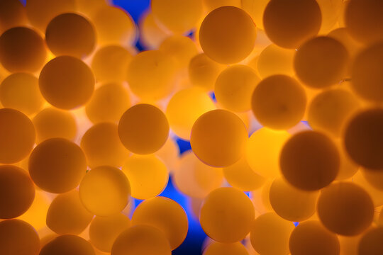 A close-up view of numerous yellow balls densely packed together with a few gaps showing a blue background