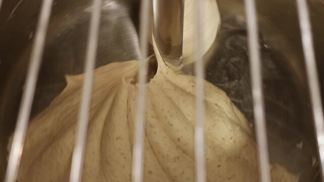 Bread dough being mixed in industrial mixer, kneading process in bakery kitchen, preparation stage before fermentation and baking