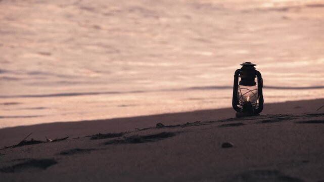 夕暮れの砂浜に置かれたアンティークなハリケーンランタン
