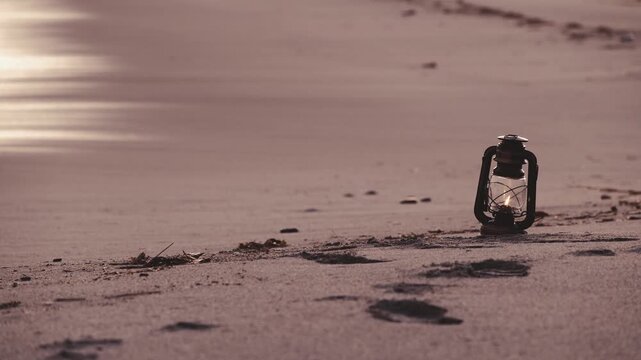 夕暮れの砂浜に置かれたアンティークなハリケーンランタン
