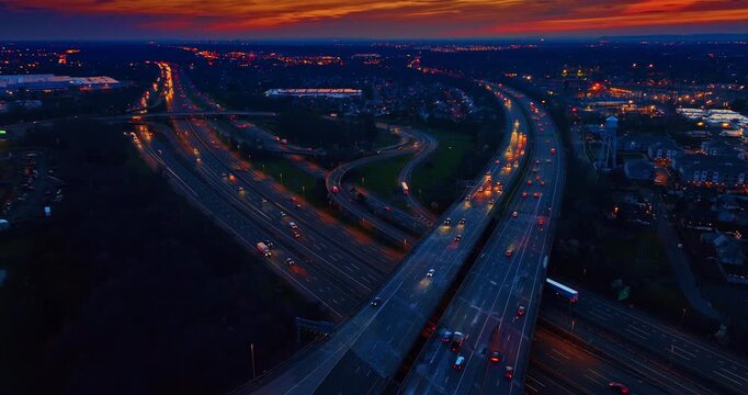 Flow of cars with their headlights on move by the multi-lane parallel highways and trestles. Commuting around the city at dusk time.