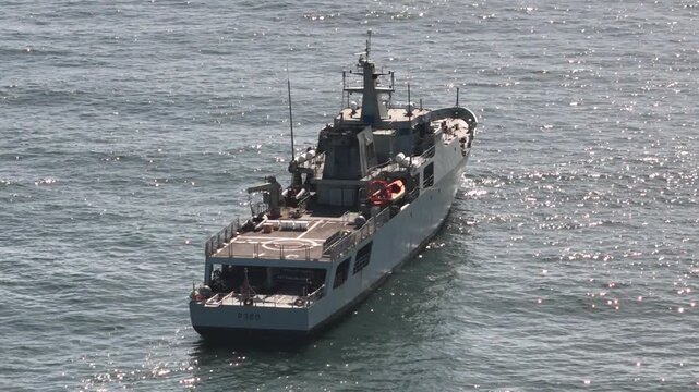 Cascais, Portugal - 22 April 2026: Aerial view of a grey naval patrol ship navigating the sparkling blue waters of the Atlantic Ocean near the coast.