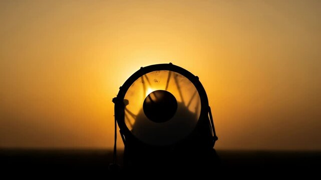 Drum silhouette against a golden sunset, with sunlight shining through the drumhead
