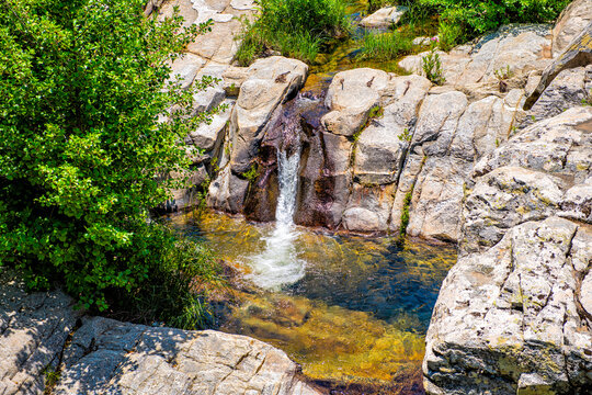 Waterfall spring from cliff mountains rocks on Ikaria island, Greece in summer with nature landscape view at longevity blue zone Magganitis