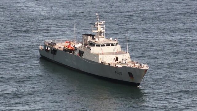 Cascais, Portugal - 22 April 2026: Aerial view of a grey naval patrol vessel anchored in the Atlantic Ocean with calm waves and clear daylight.