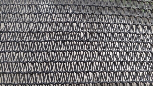 Close-up photo of black shade net with repeating pattern and unique texture.