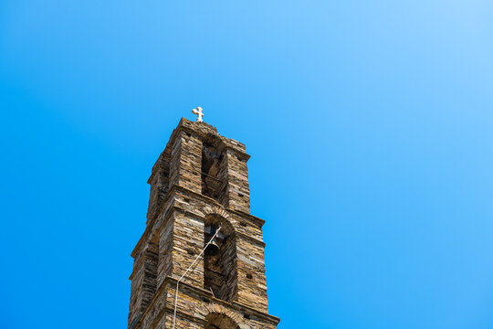 Arethousa village with Saint St Marina Greek Christian Orthodox church bell tower building slate architecture on Ikaria, Greece with broken cross