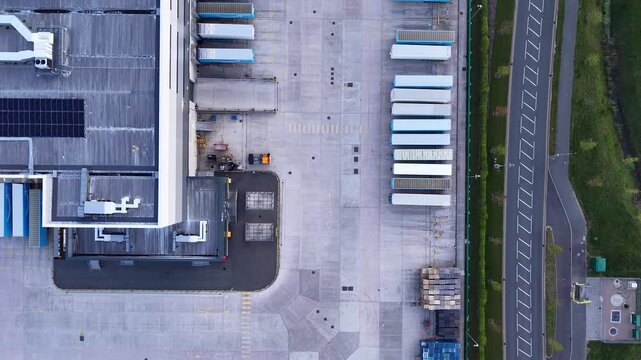 Birmingham, United Kingdom - 20 April 2026: Aerial view of the Amazon EMA4 UXD1 logistics center with semi-truck trailers parked at loading docks.