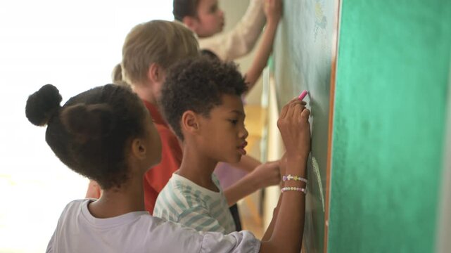 Diverse students writing on chalkboard in classroom, representing active learning and participation in education