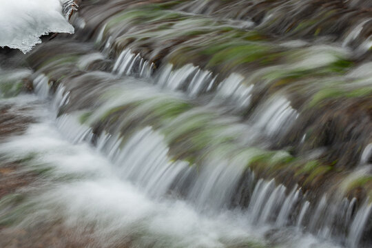 Winter landscape of a cascade at Austrian Falls framed by ice and captured with motion blur, Michigan's Upper Peninsula, USA