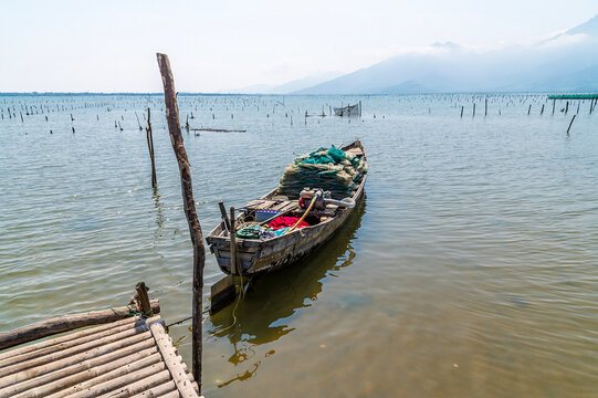 A view of a boat moored to a jetty used to access an oyster farm on the Lap An Lagoon in Vietnam on a bright sunny day