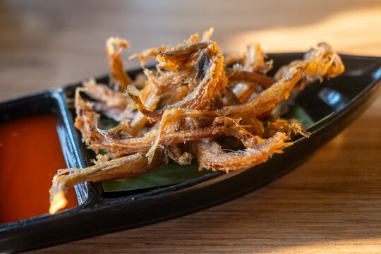 Fried Bombay Duck fish served on a plate with spicy sauce