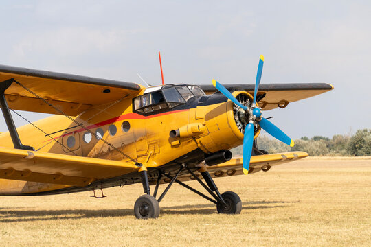 A parked yellow biplane old Soviet-made transport plane on a grassy airfield