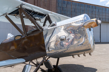 Vintage silver-brown biplane aircraft parked near hangar © ZenitX