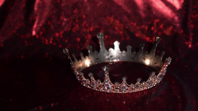Refined golden crown with gemstones on red textured background, symbol of luxury and high status.