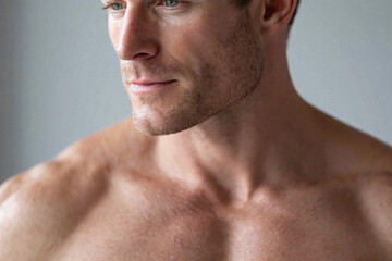 Naklejka premium Handsome male chest with smooth hydrated skin and natural light showing subtle stubble and relaxed expression